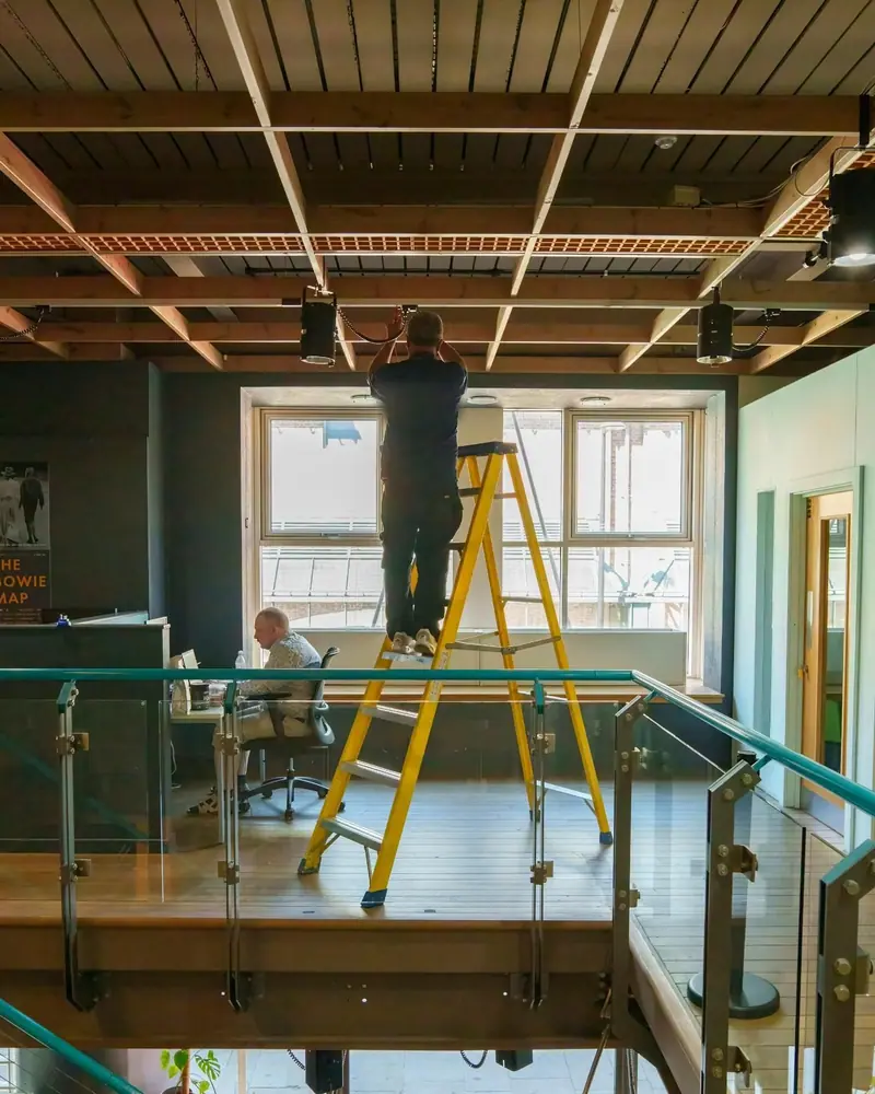 Group engineer installing a fire alarm at ceiling height