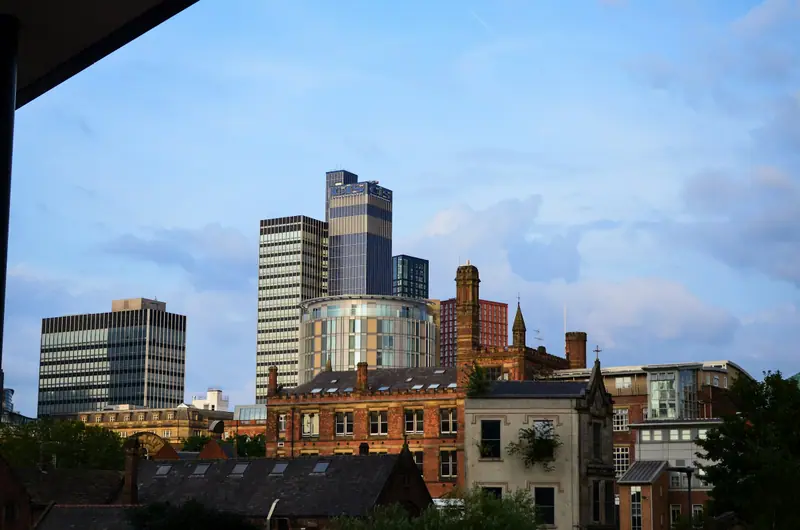 New residential towers rising behind historic red brick buildings in Manchester